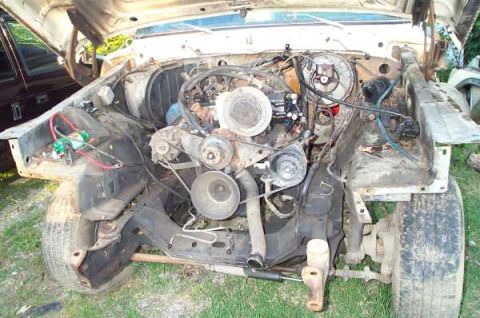 1979 Ford Bronco - The engine compartment of an older SUV is exposed, with the hood open, revealing the engine and surrounding components.