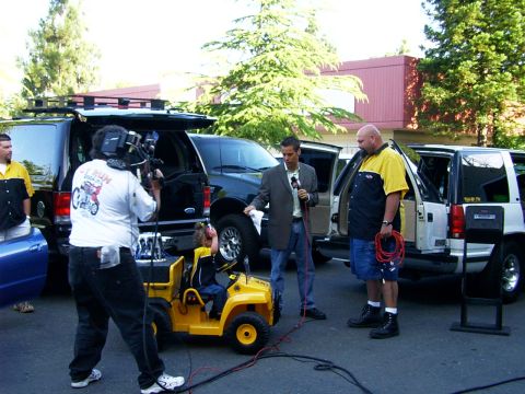 2000 Ford Excursion - A news crew is filming an outdoor segment with several people and vehicles present.