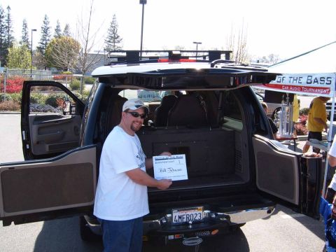 2000 Ford Excursion - A man stands with a certificate in the open rear of an SUV at a car audio tournament.