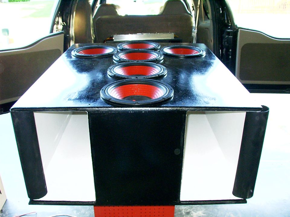 Custom subwoofer box with six red-coned subs in the cargo area of an SUV