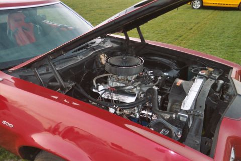 1972 Ford Ranchero - The engine bay of a red 1972 Ford Ranchero is open, revealing its V8 engine and custom air intake.