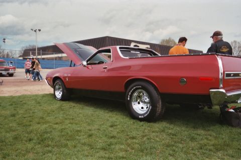 1972 Ford Ranchero - A red 1972 Ford Ranchero is displayed at a car show with its hood open, showing off its engine bay.