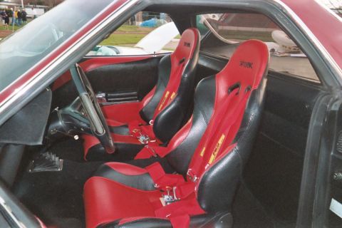 1972 Ford Ranchero - The interior of a car features two racing seats with red harnesses and a manual shifter.