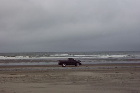 1996 Ford Bronco - Pickup truck on the beach under an overcast sky.