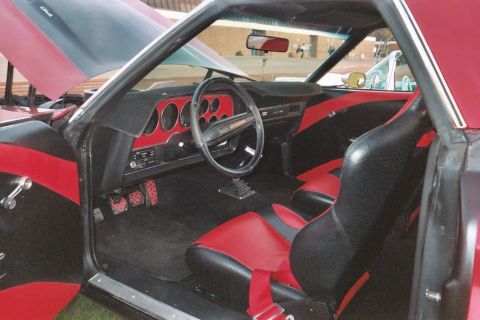 1972 Ford Ranchero - The interior of a 1972 Ford Ranchero shows custom red and black upholstery and a dashboard with multiple gauges.