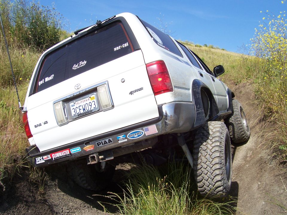 Rear quarter of a white Toyota 4Runner with plate 3CFW093 and mud tire in a hillside rut