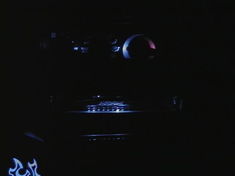 1999 Ford Taurus - The dimly lit interior of a car shows glowing dashboard lights and a decorative flame decal on the door.