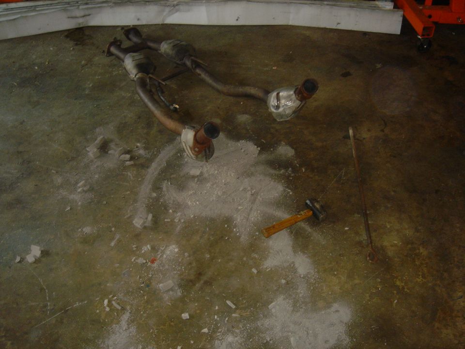 Exhaust system parts on concrete floor with hammer