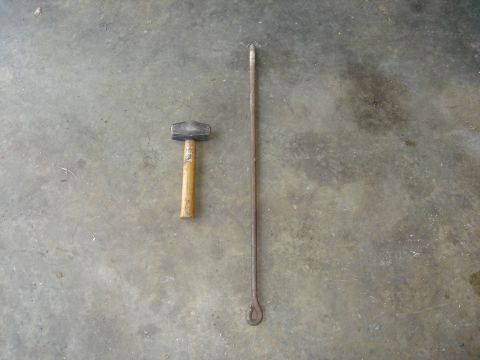 1986 Ford Mustang - Tools laid out on a garage floor, including a hammer and a long pry bar with a looped end.