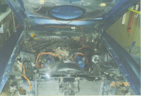1972 Ford Mustang - The engine bay of a blue vehicle is shown with the hood raised, revealing the engine and associated components.