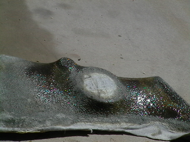 Close-up of a damaged car bumper part with a textured, wet surface