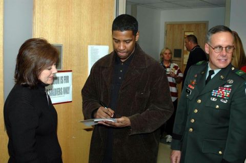1996 Ford Probe - Denzel Washington signs autographs for fans in a hallway, with a military officer and other individuals present.