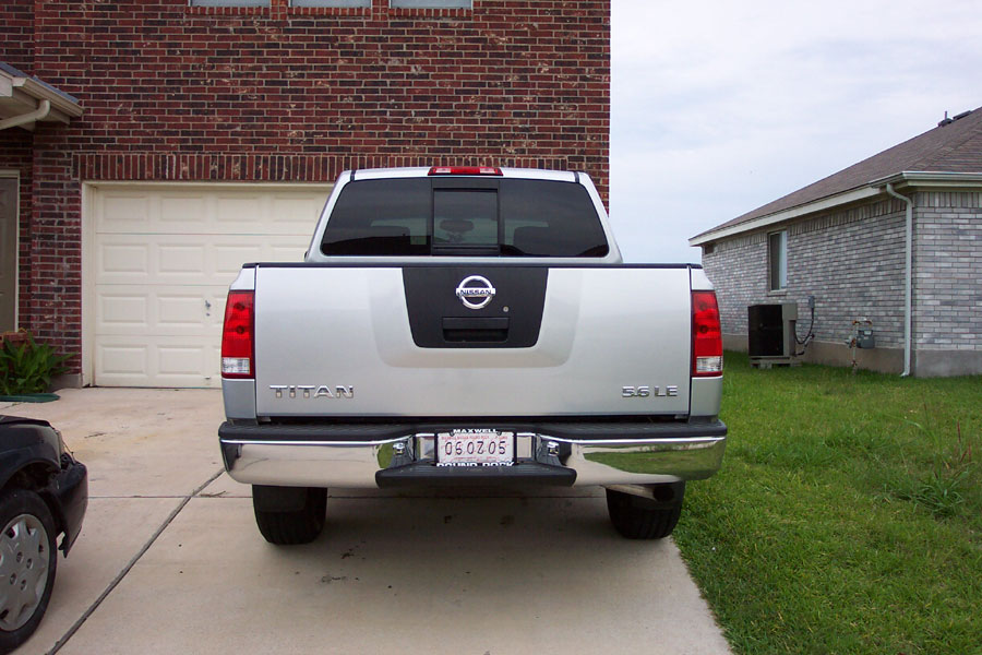 Silver Nissan Titan pickup rear view in a driveway showing TITAN and 5.6 LE badges