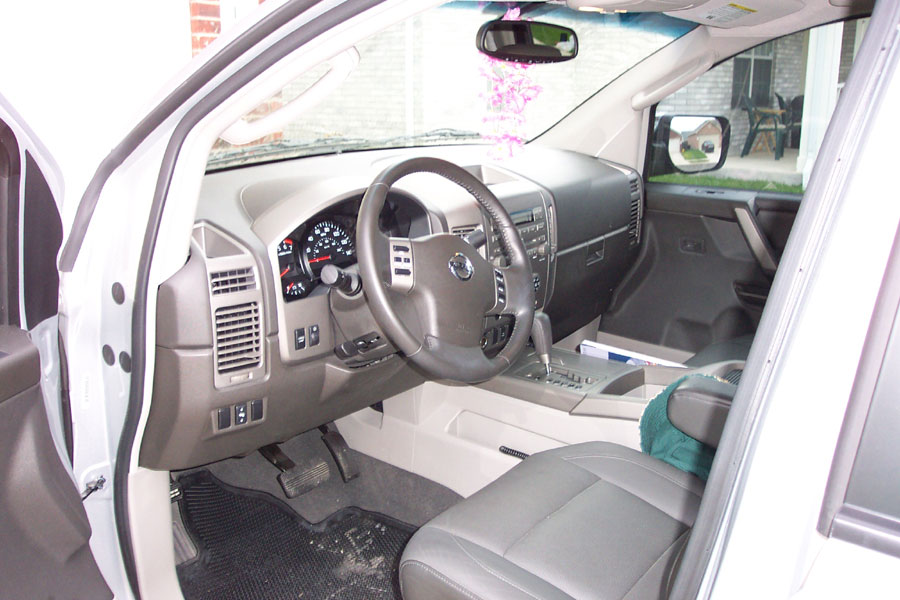Grey leather driver's-side interior of a Nissan truck, door open