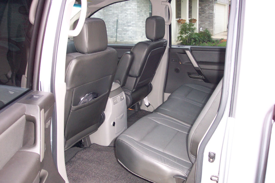 Charcoal leather rear bench seat in a white crew-cab pickup, door open