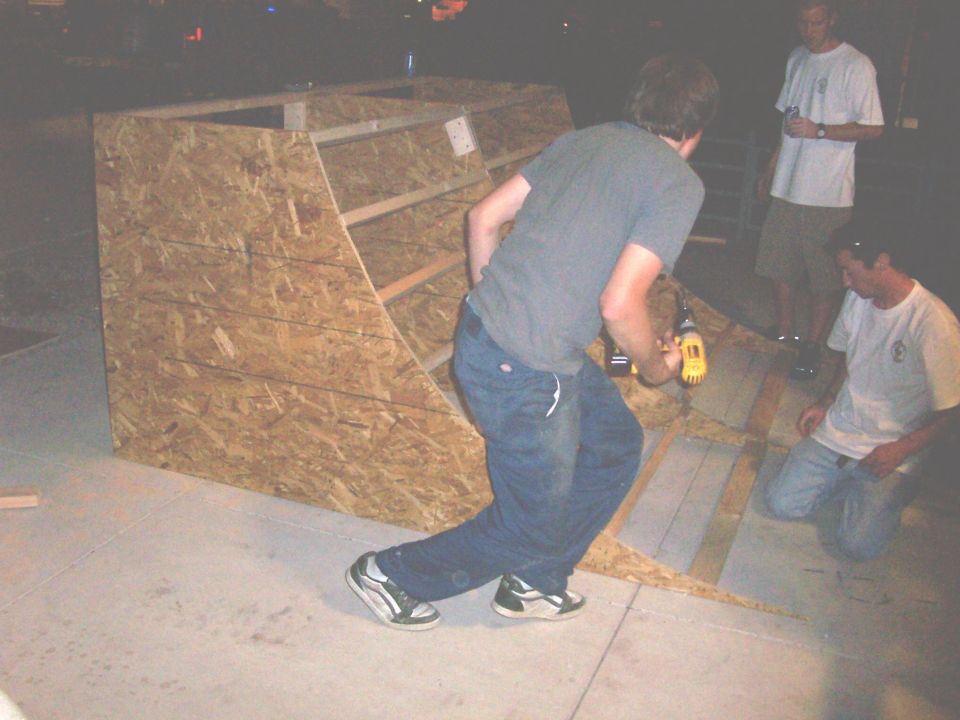 People building a wooden ramp, one person using a drill