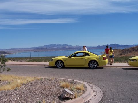 2002 Ford GT - A yellow coupe with a spoiler is parked by a lake, with two other vehicles visible.