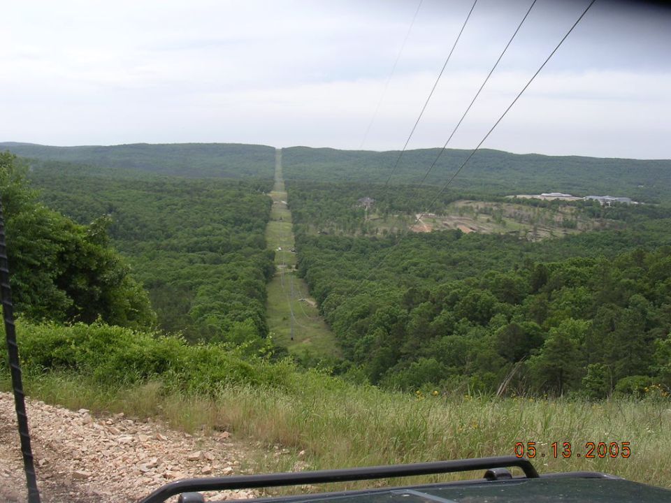 View from a vehicle looking out over a vast forest with a long, straight clearing for power lines stretching to the horizon