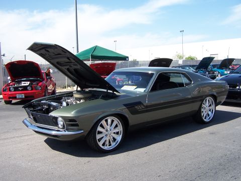 2002 Ford GT - A modified 1970 Ford Mustang Boss 302 is displayed with its hood open, alongside other vehicles.