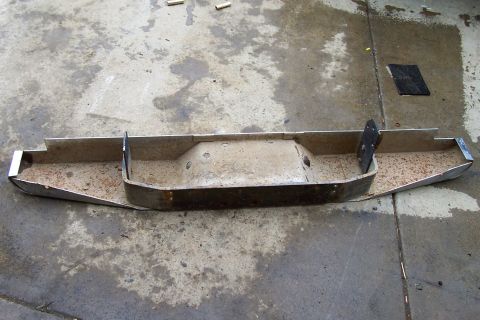 1994 Ford F-150 - A detached metal truck bumper lies on a concrete surface, showing signs of wear and tear.