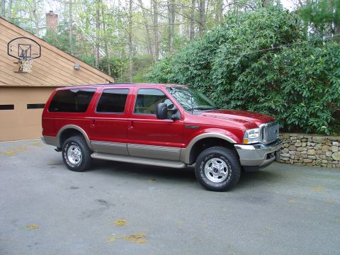 2002 Ford Excursion - This Ford Excursion SUV is parked in front of a garage and trees.
