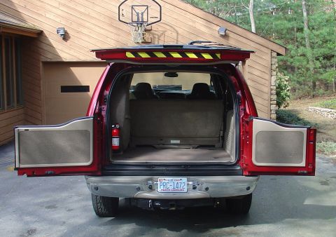 2002 Ford Excursion - Rear view of a red Ford Excursion with its cargo doors open, parked in front of a garage.