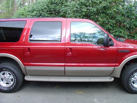 2002 Ford Excursion - Red 2002 Ford Excursion SUV shown from the side with tan lower body trim and running boards.