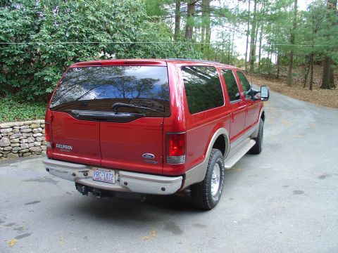 2002 Ford Excursion - Rear view of a red Ford Excursion SUV with tan lower body trim and a tow hitch.