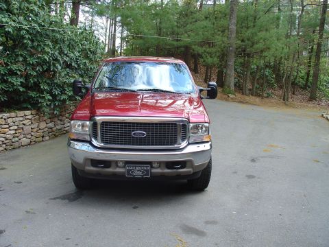 2002 Ford Excursion - A red Ford Excursion is parked in front of a wooded area. The license plate frame reads 'Black Mountain Ford'.