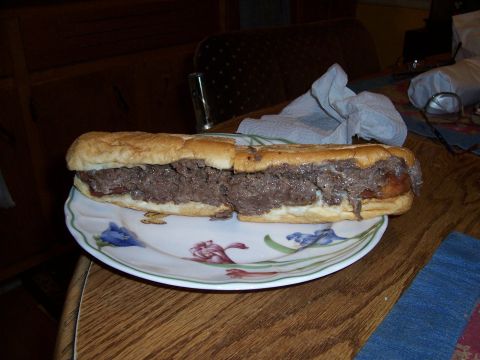 1995 Ford Bronco - A large sandwich filled with meat sits on a decorative plate on a wooden table.