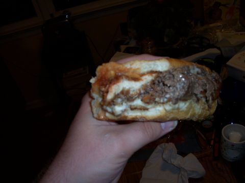 1995 Ford Bronco - A hand holds a large sandwich filled with meat and sauce.