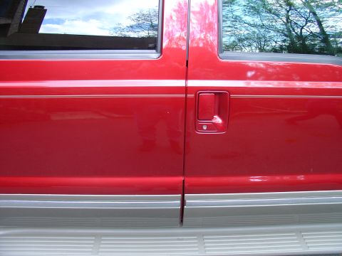 2002 Ford Excursion - The side of a red Ford Excursion is shown, a two-tone paint scheme with silver trim along the bottom.