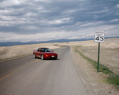 1996 Ford Probe - Red 1996 Ford Probe cruises down a desolate highway under a cloudy sky.