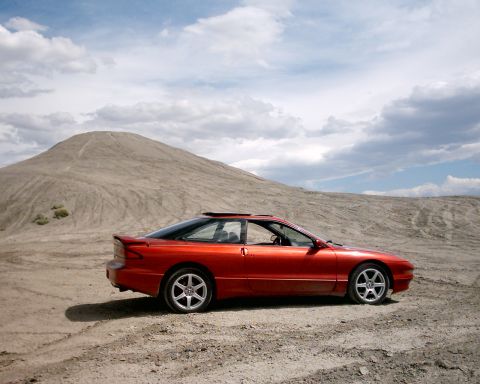 1996 Ford Probe - A 1996 Ford Probe sits in a dusty, arid landscape under a cloudy sky.