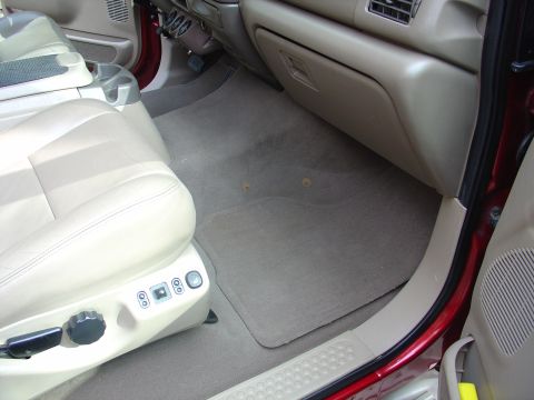 2002 Ford Excursion - The interior of a large SUV, tan leather seats and a tan dashboard, is shown from the passenger side.