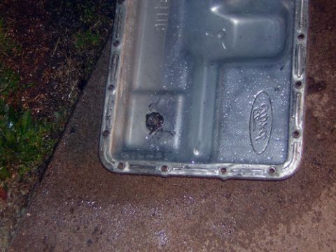 1995 Ford Bronco - Close-up of a Ford transmission pan, showing the embossed Ford logo and drain plug.