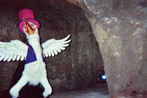 1968 Ford Mustang - A costumed character, resembling a bird, stands with wings outstretched in a dimly lit, rocky environment.