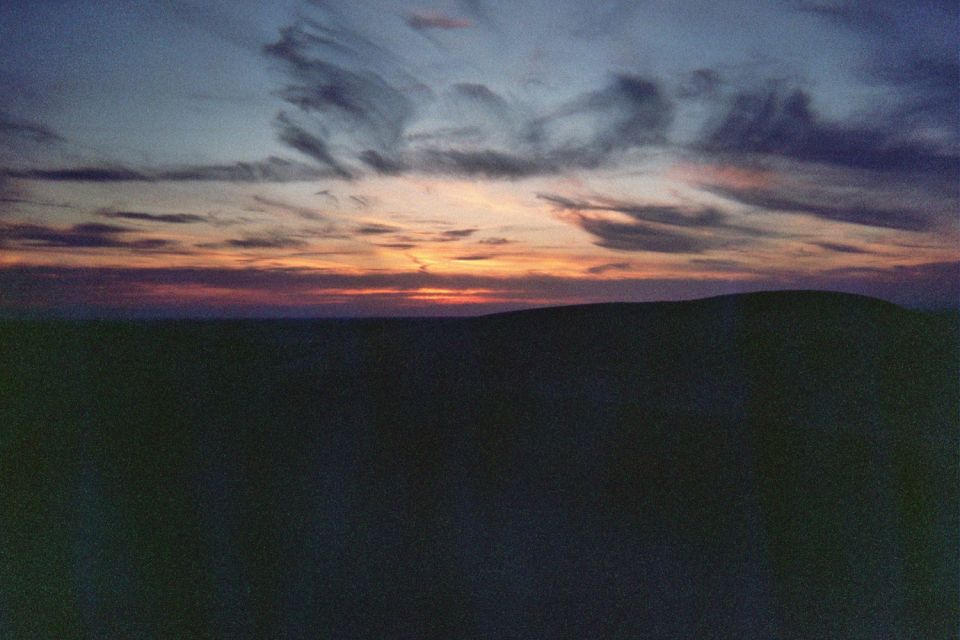 Sunset over desert dunes with wispy clouds