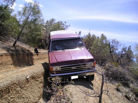 1989 Ford Bronco - A Ford Bronco navigates a rough, off-road trail under a clear blue sky.