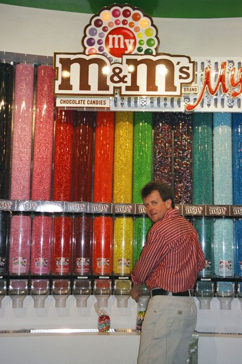 1994 Ford Bronco - A man is seen in front of a large display of M&M's candy dispensers, a variety of colors.