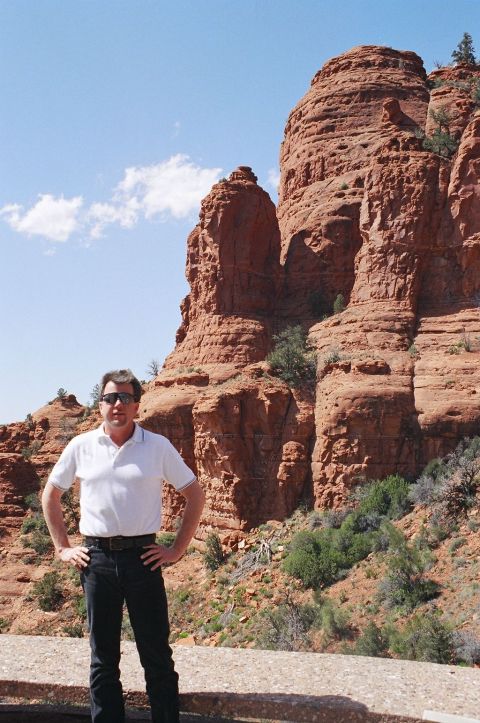 1994 Ford Bronco - A man poses for a photo in front of dramatic red rock cliffs and desert vegetation.