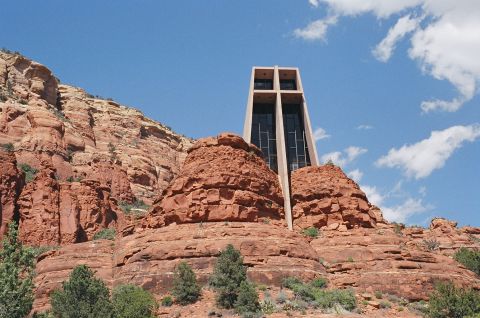 1994 Ford Bronco - A modern chapel is built into the side of a red rock formation under a partly cloudy sky.