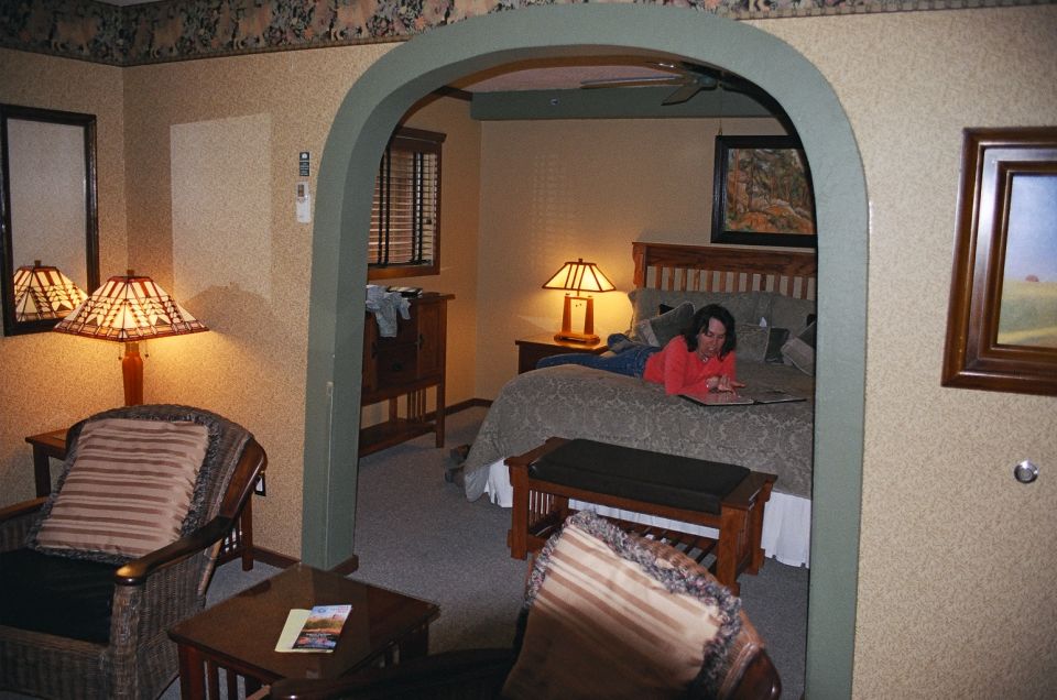 Interior of a room with a bed, a person lying on it, and furniture. Archway leads to another part of the room