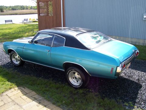 1971 Chevrolet Chevelle - A blue 1971 Chevrolet Chevelle coupe with a black roof is seen from the rear three-quarter angle next to a building.