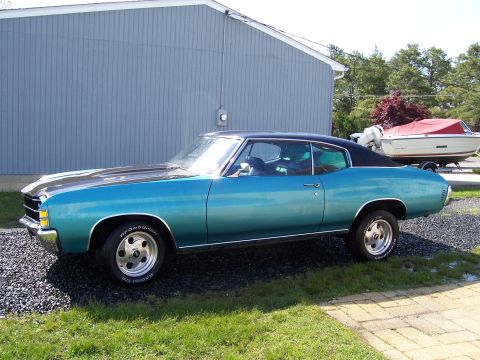 1971 Chevrolet Chevelle - This 1971 Chevrolet Chevelle coupe features a striking teal paint job and a contrasting black vinyl roof, seen parked outdoors.