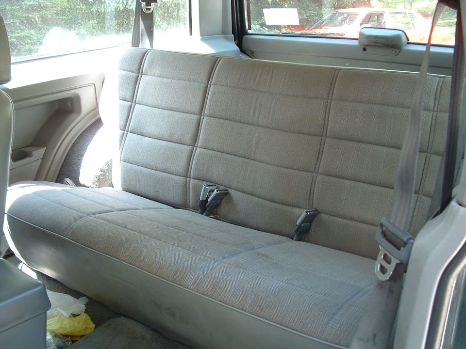 back seat and seatbelts inside a vehicle, with another car visible through the window