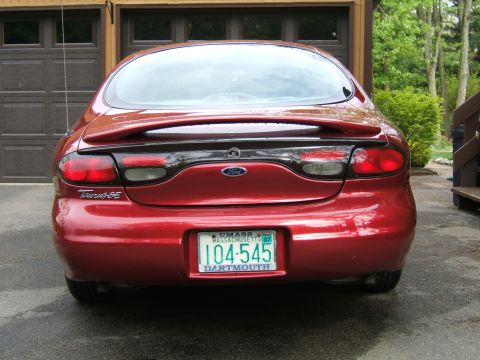 1998 Ford Taurus - Rear view of a red 1998 Ford Taurus SE parked in front of a garage.
