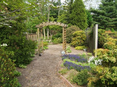 1998 Ford Taurus - A gravel path winds through a lush garden, passing under a wooden arbor and past flower beds.