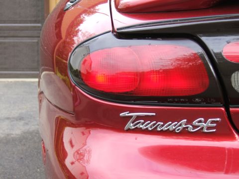 1998 Ford Taurus - Rear view of a red 1998 Ford Taurus SE, showing the taillight and 'Taurus SE' emblem.