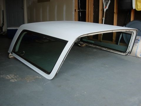 1995 Ford Bronco - A detached white vehicle canopy with dark tinted windows is stored indoors.
